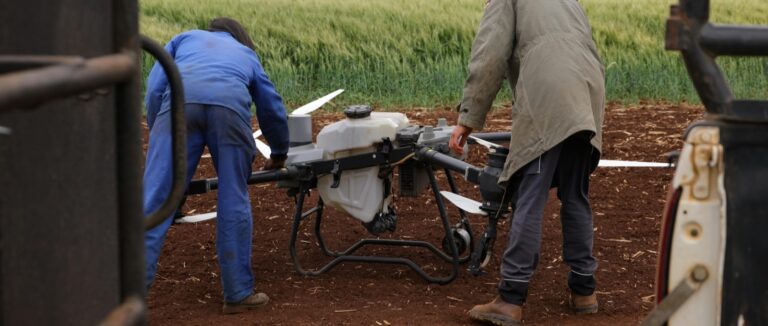Two people preparing a drone beside a field - a good example of agtech at play.