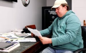 Person at messy desk looking at paper.